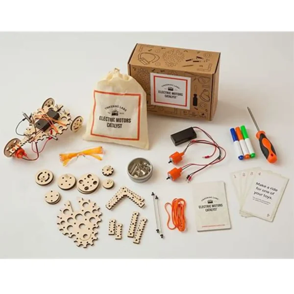 Full layout of the Electric Motors Catalyst kit including wooden parts, motors, wires, markers, cards, a screwdriver, and a drawstring bag.