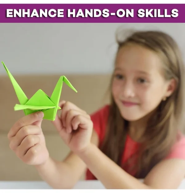Young girl holding a green origami crane, smiling and showing her completed craft.