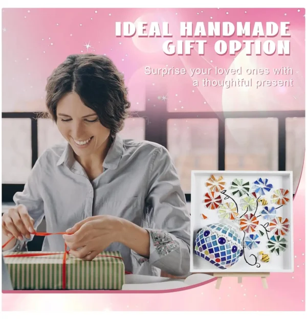 A smiling woman wraps a gift box with a red ribbon next to a handmade mosaic and rope flower painting displayed on a mini easel.